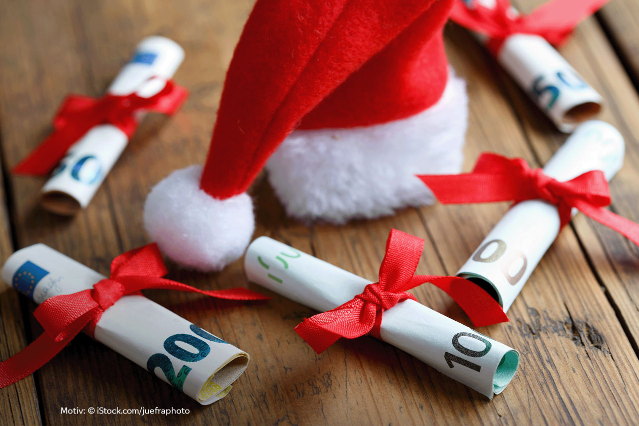 Mehrere eingerollte Scheine mir roten Schleifen und einer Weihnachtsmütze