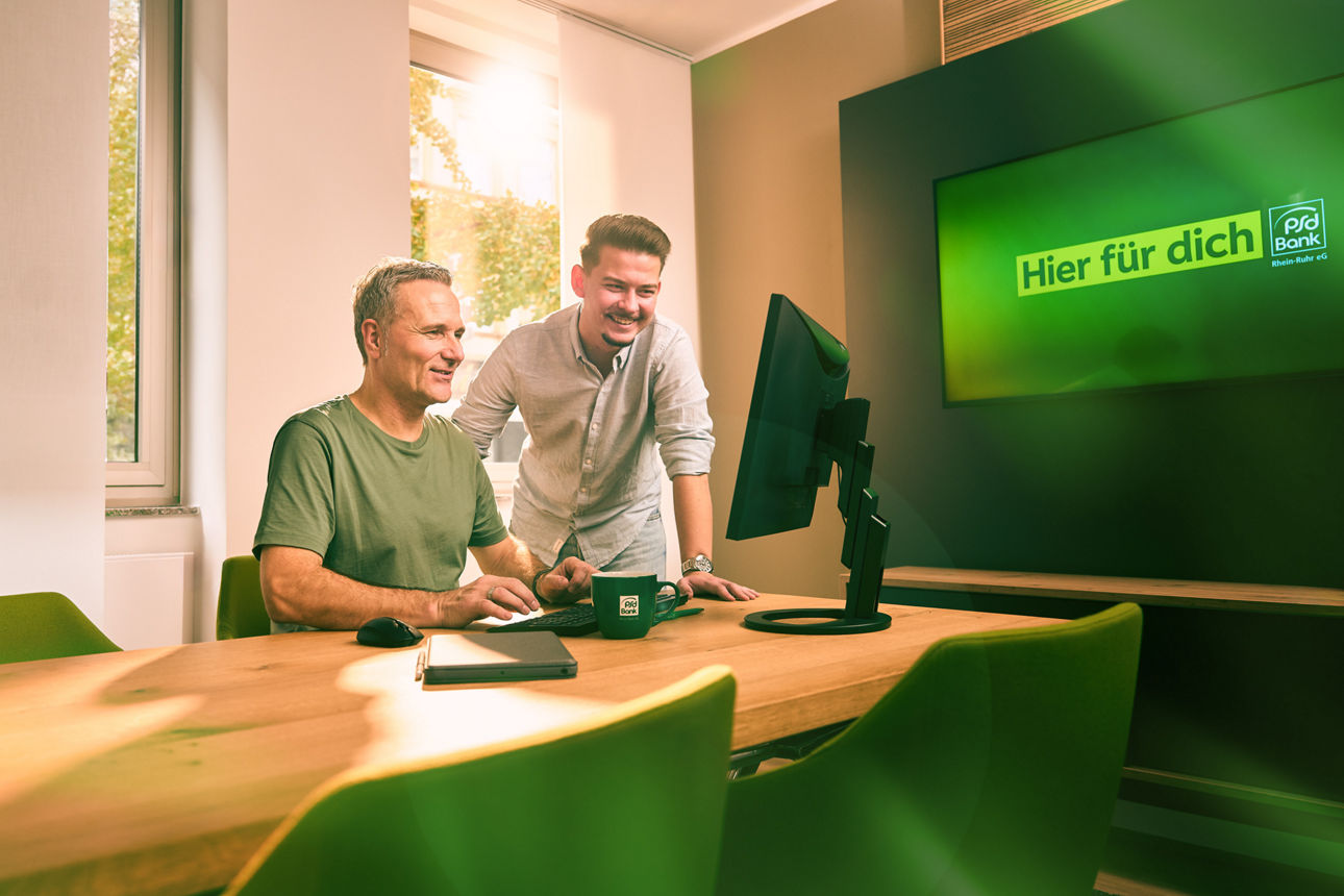 Mitarbeitende der PSD Bank, die an zusammen am PC arbeiten