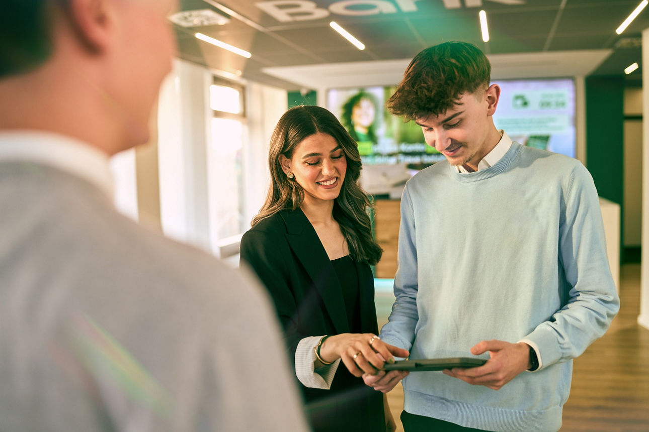 Zwei Auszubildende der Bank arbeiten mit einem Tablet in der Hand