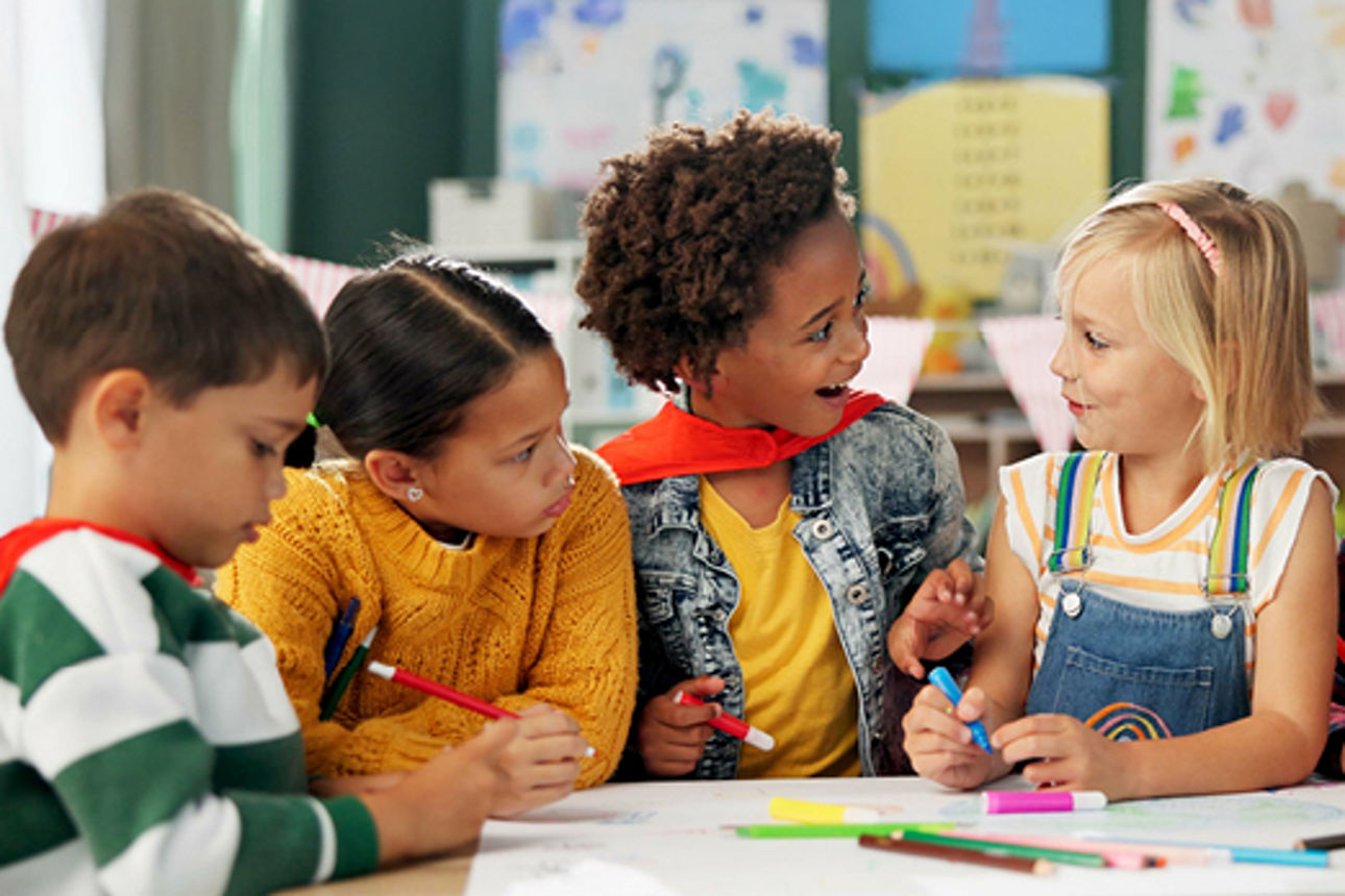 Kindergartenkinder sitzen am Tisch unterhalten sich und malen