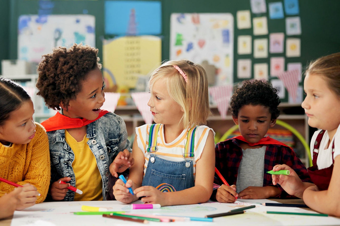 Eine Gruppe Kinder sitzen eng an einem Tisch in der Schule