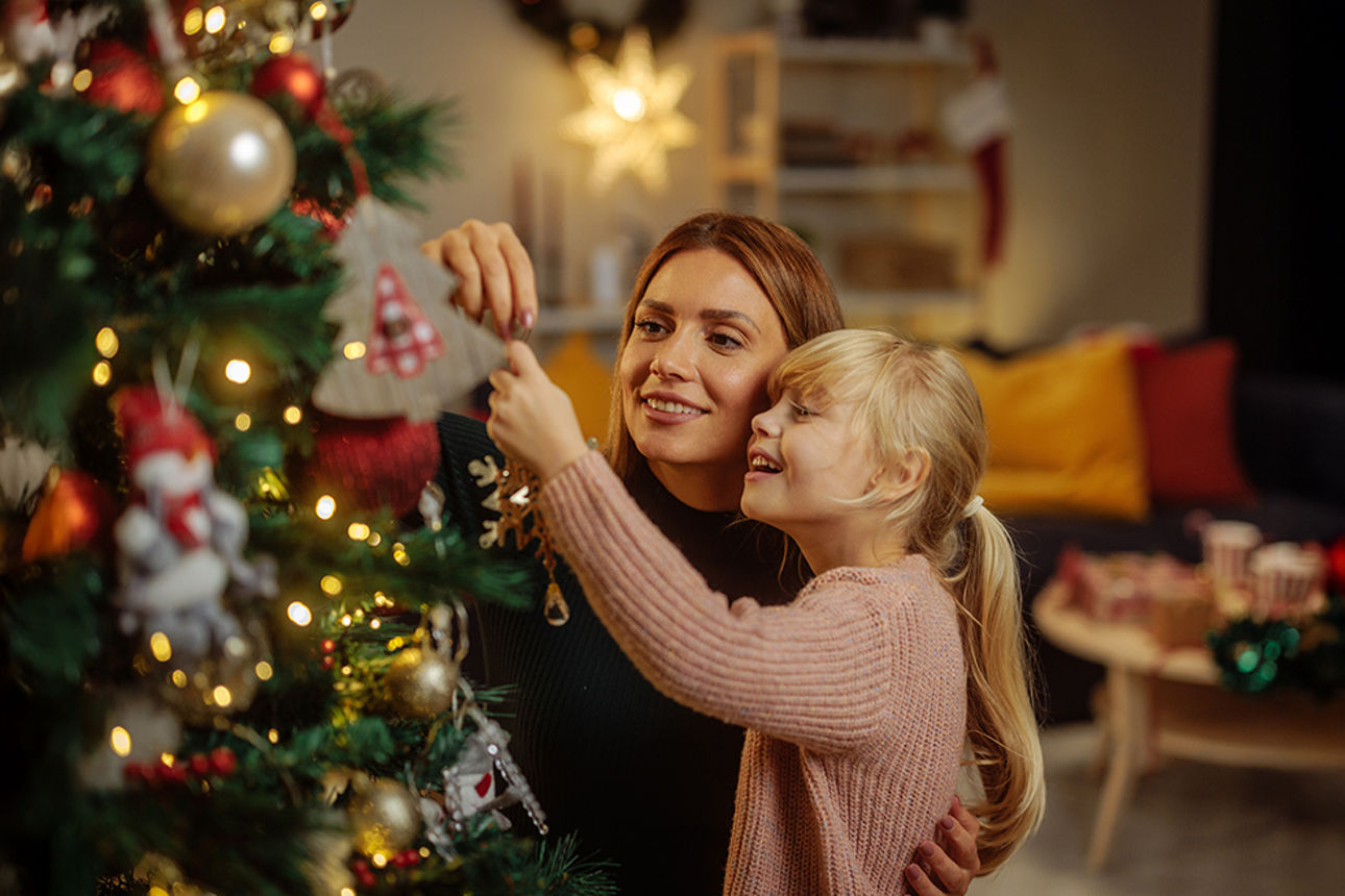 Eine Mutter schmückt mit ihrer Tochter einen Weihnachtsbaum