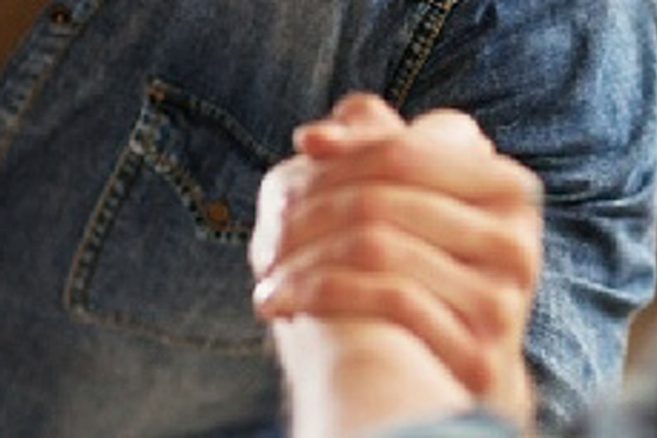 Das Bild zeigt eine Nahaufnahme von zwei Menschen, die sich an den Händen halten.