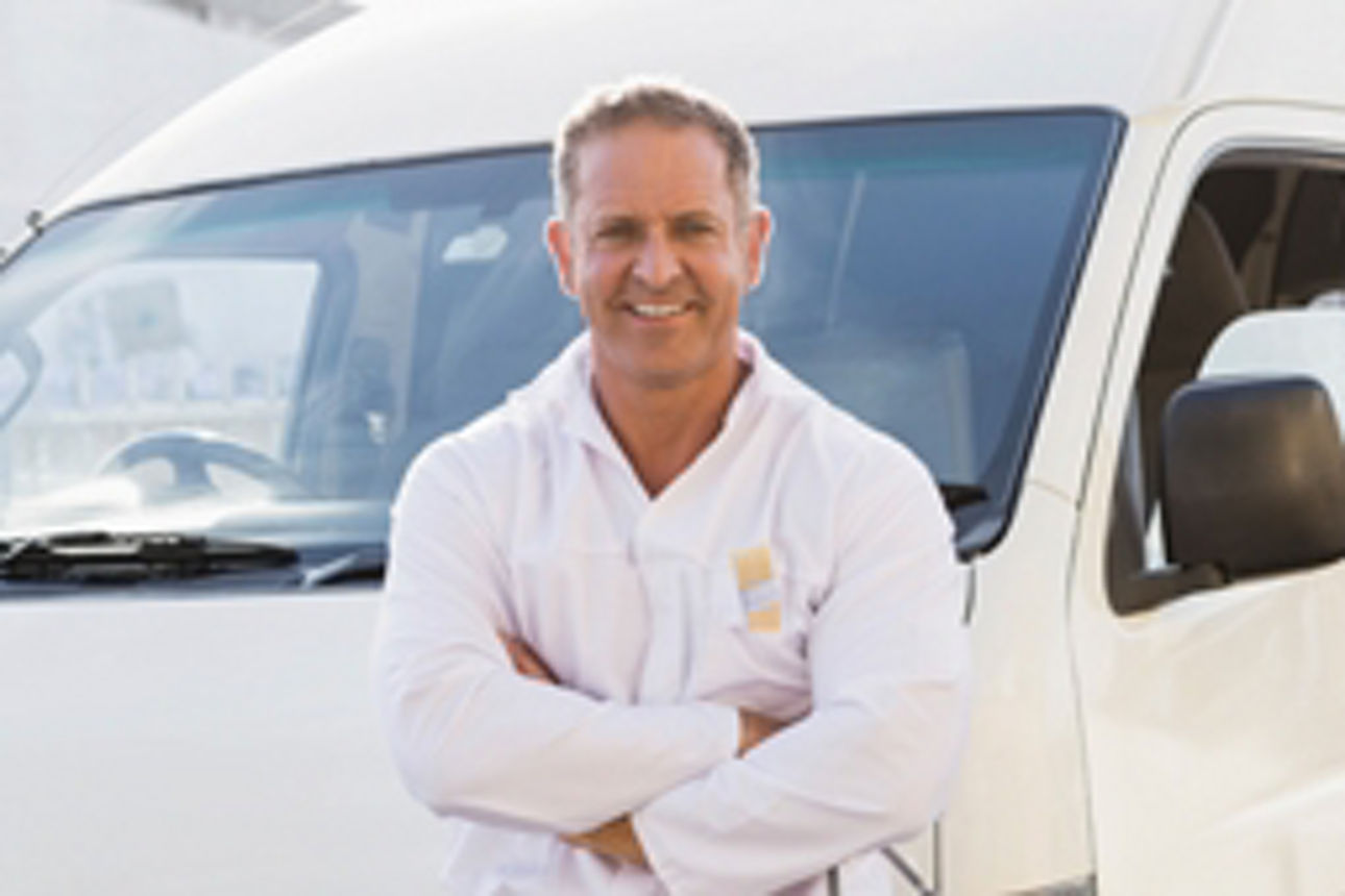 Ein Mann in weißer Latzhose steht neben einem weißen Lieferwagen