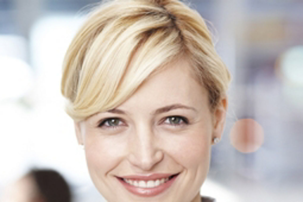 Eine Frau mit einem warmen Lächeln, die ihre Freude und Positivität in einer hellen, einladenden Umgebung zum Ausdruck bringt