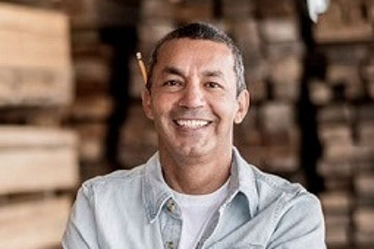 Ein Mann steht vor einem großen Holzstapel