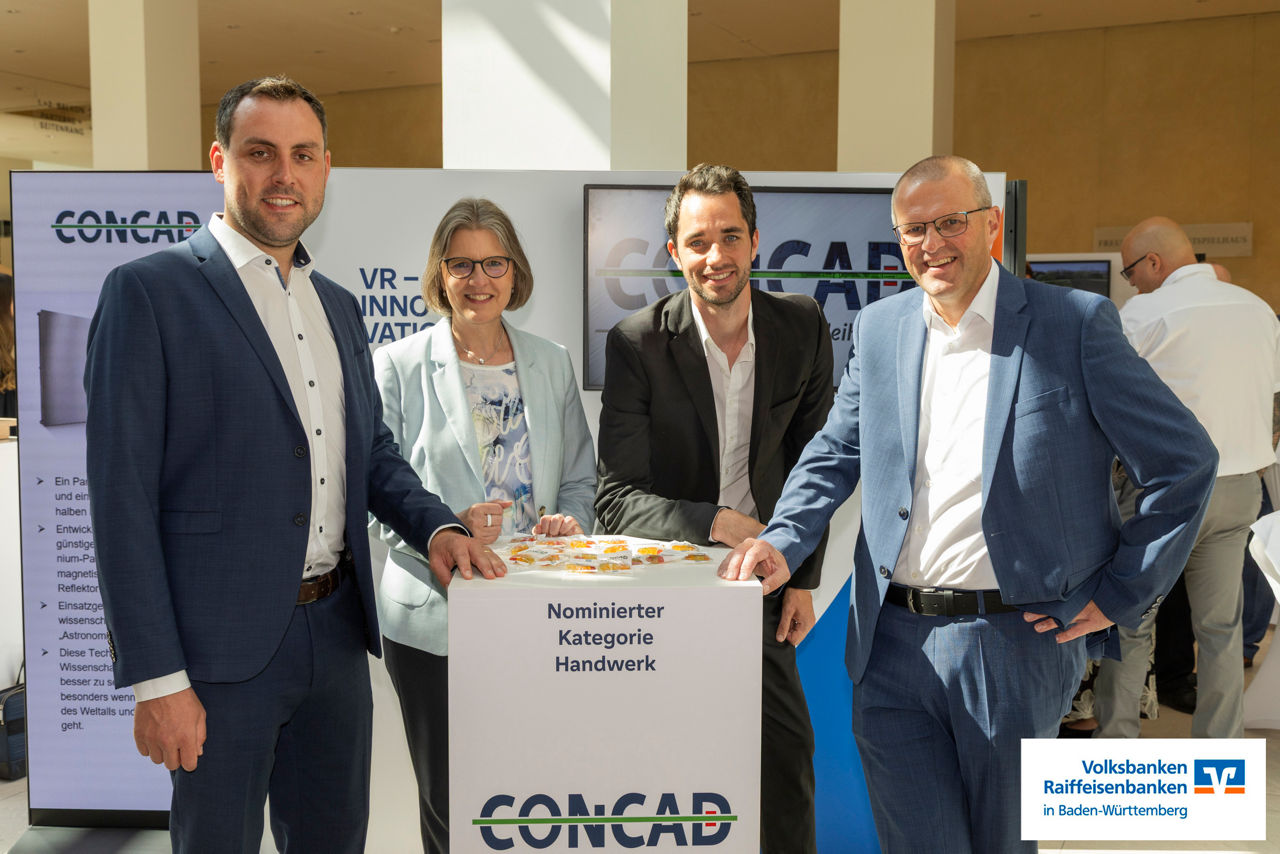 vier Personen der Firma Concad und der Volksbank Franken stehen bei der Preisverleihung um einen Stehtisch 