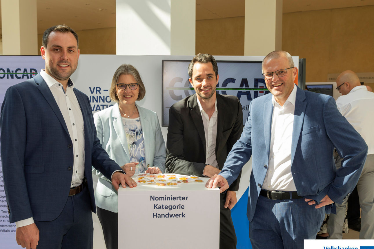 vier Personen der Firma Concad und der Volksbank Franken stehen bei der Preisverleihung um einen Stehtisch 