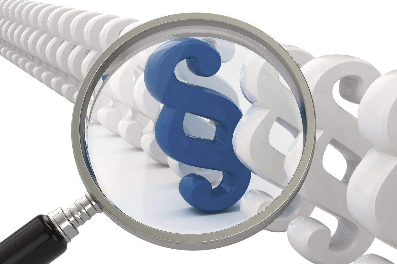 Eine Lupe vergrößert ein blaues Paragrafenzeichen zwischen mehreren weißen Paragrafenzeichen.