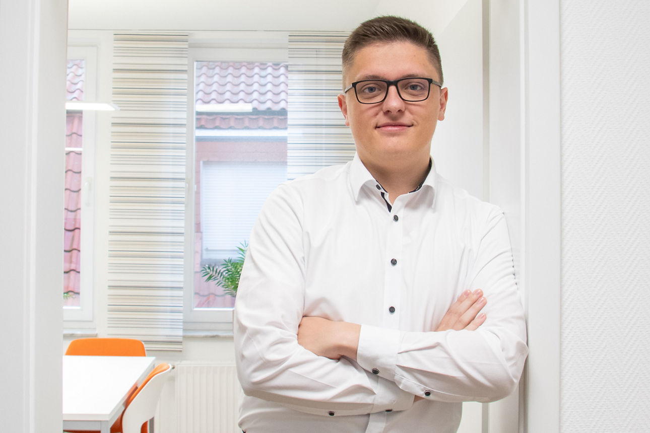 Ein Mann in Hemd steht angelehnt an einen Türrahmen