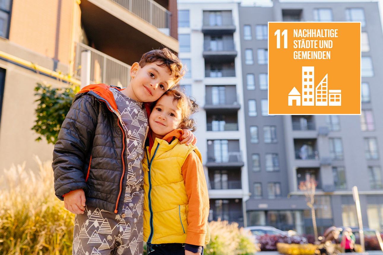 Ein Junge und ein Mädchen stehen Arm in Arm vor einem Hochhauskomplex, daneben Icon "Nachhaltige Städte und Gemeinden"
