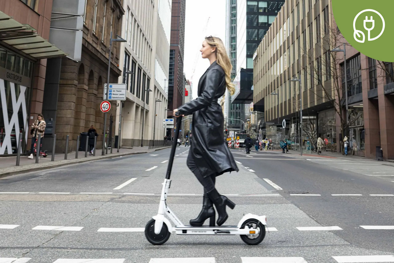 Junge Frau fährt mit einem E-Roller auf einem Radweg in der Stadt