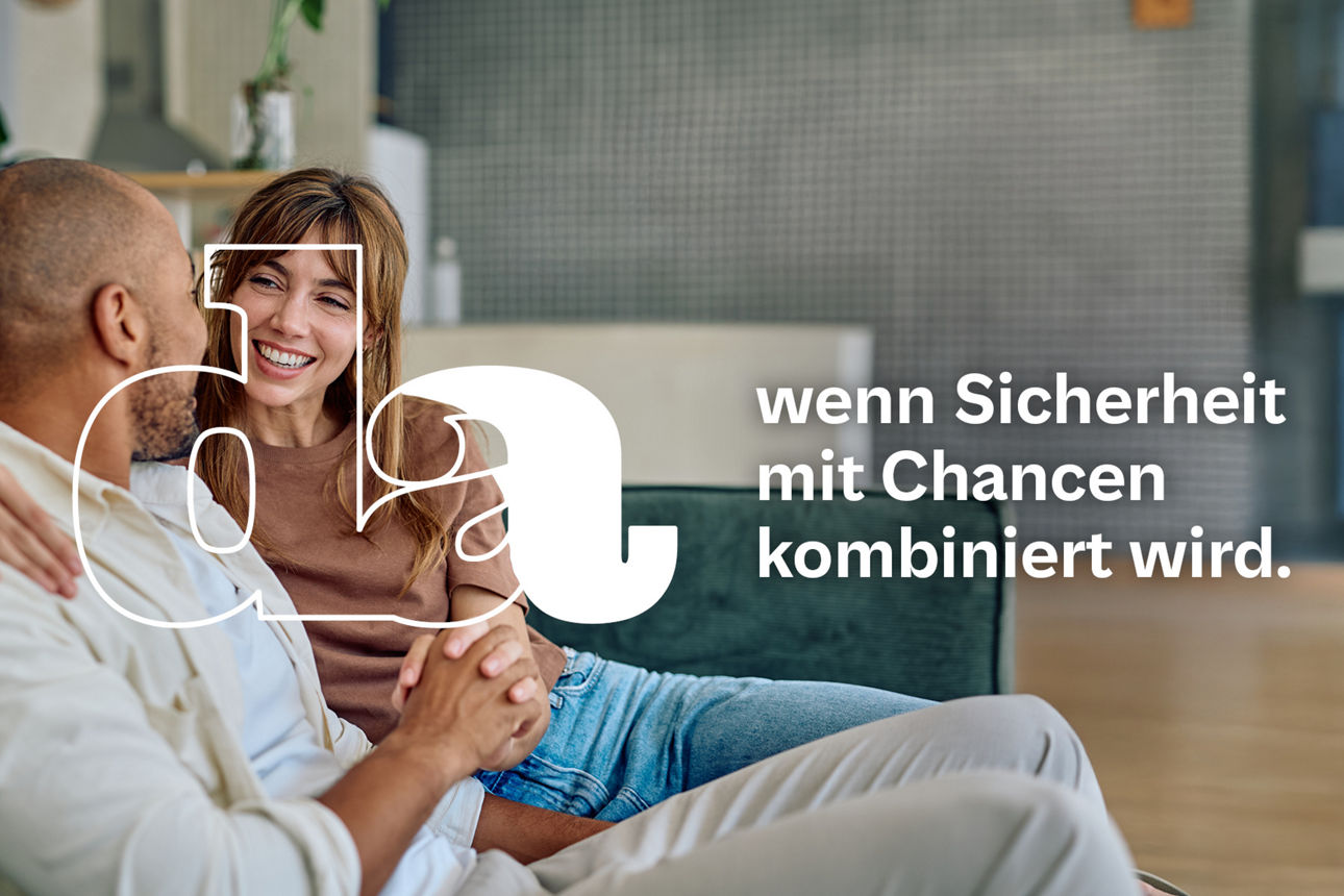 Paar sitzt entspannt auf dem Sofa in modern eingerichteter Wohnung hält Händchen und schaut sich liebevoll an