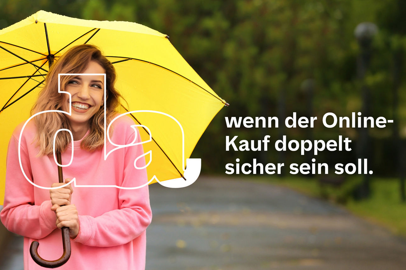 Junge Frau im pinken Pullover steht lachend im Park und hält einen geöffneten gelben Regenschirm