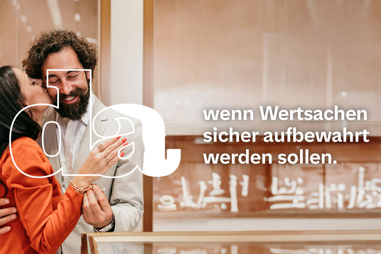 Verliebtes Paar in einem Juweliergeschäft umarmt sich freudestrahlend und stolz zeigt die Frau ihre Hand mit Ring