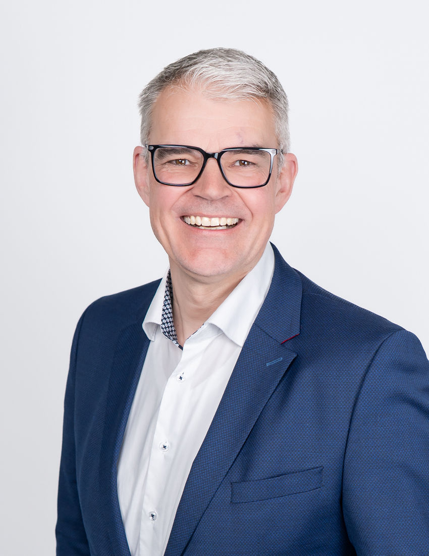 Foto unseres Vermögensberaters Christoph Dürr vor einem hellgrauen Hintergrund in einem blauen Jackett