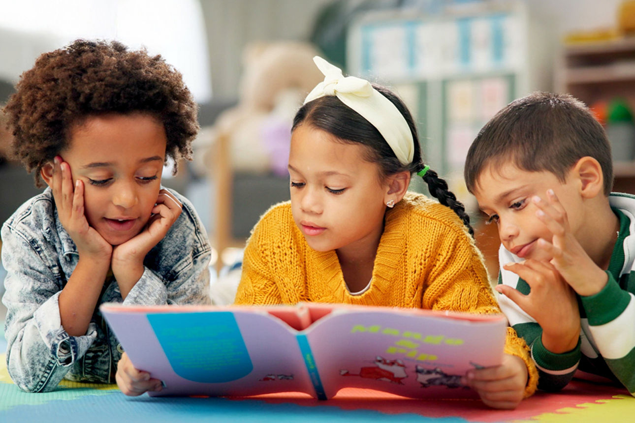 Drei kleine Kinder lesen gemeinsam ein Buch