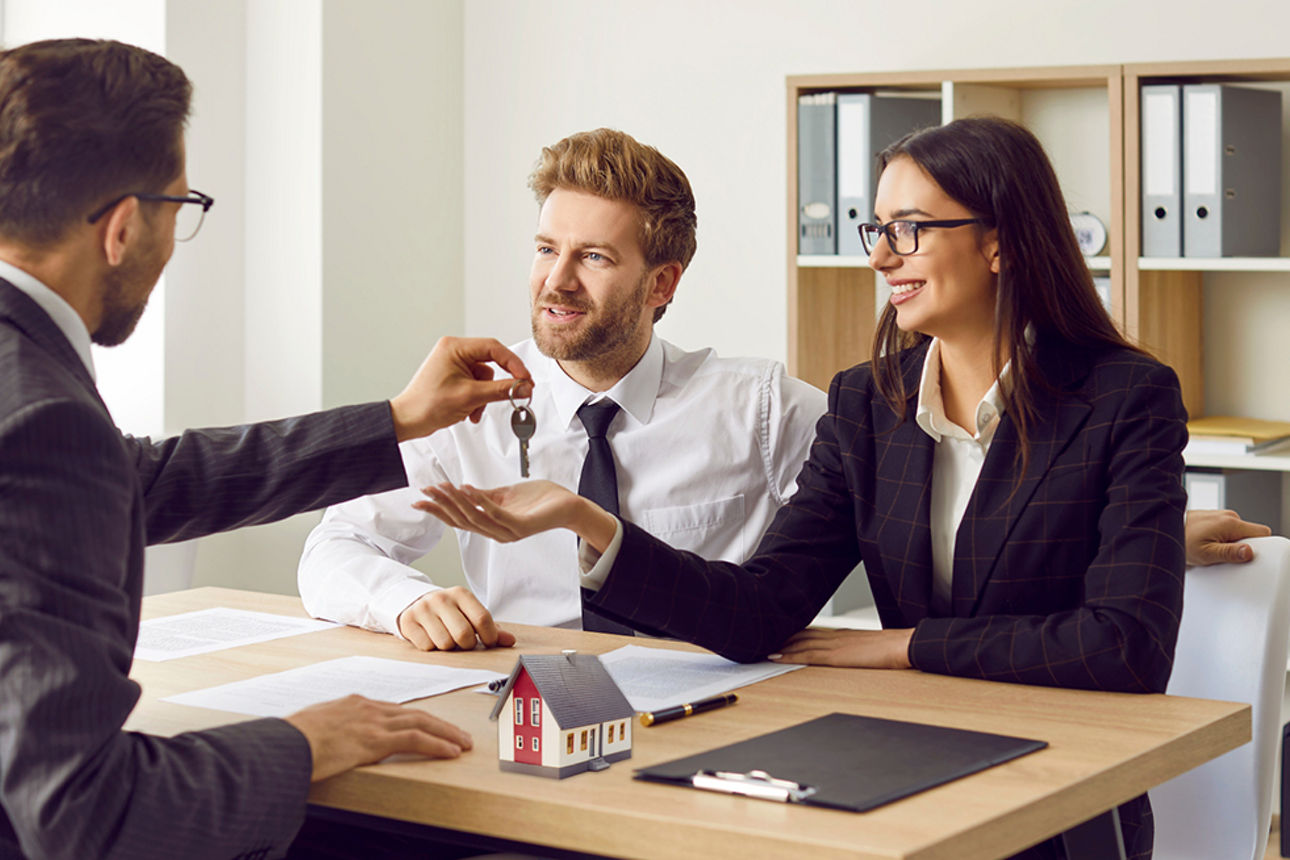 Ein Makler überreicht einem Paar einen Schlüsselbund