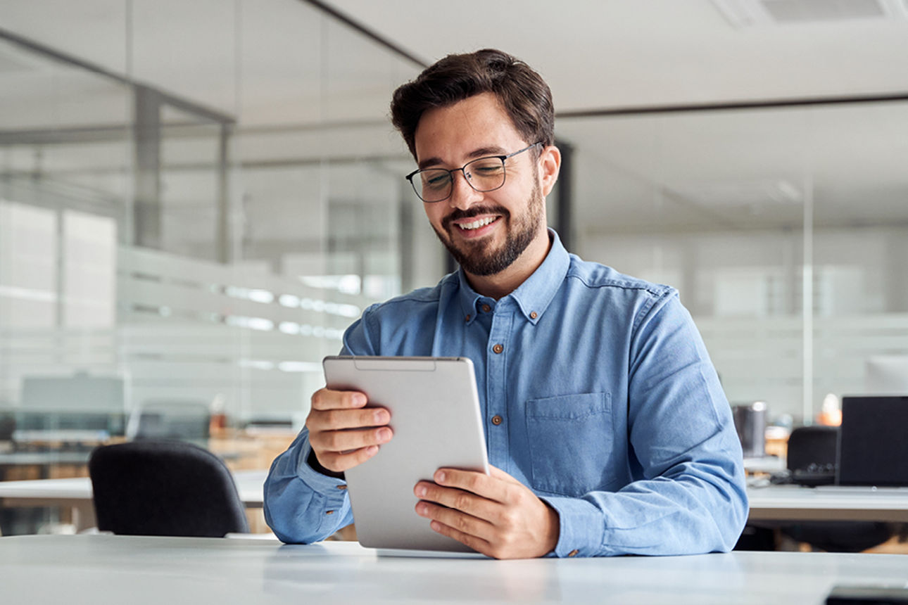 Mann mit blauem Hemd in einem Büro mit einem Tablet in der Hand