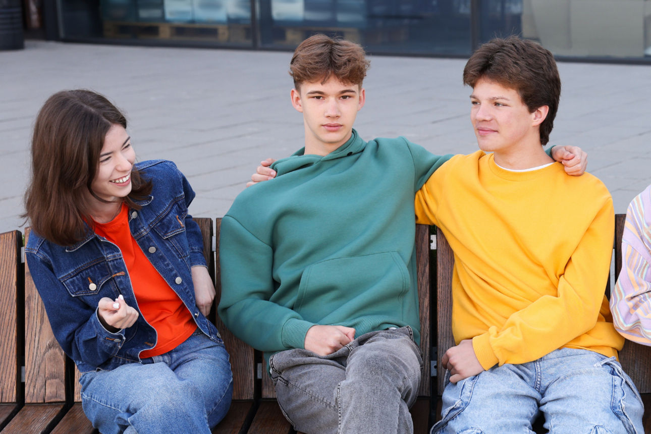Gruppe von jungen Leuten sitzen auf einer Bank