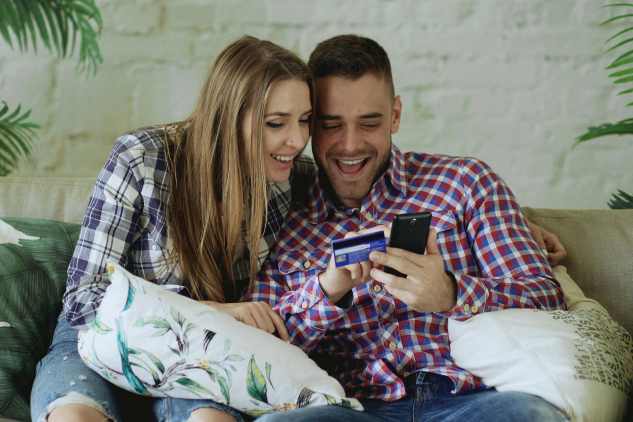 Frau und Mann sitzen auf Sofa mit einer Karte in der Hand
