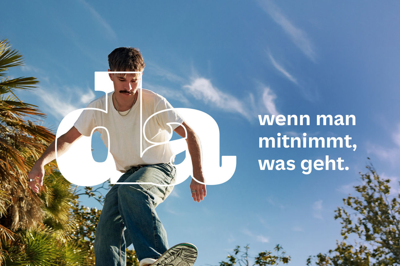 Jugendlicher steht auf einem Skateboard und fährt bergab.