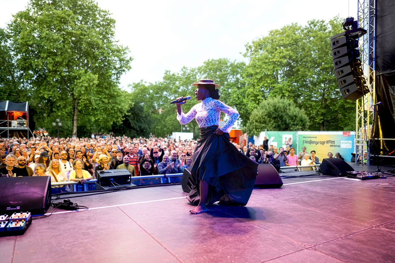 Frau singt und tanzt auf der Bühne vor zahlreichen Zuschauern. Foto: Uwe Niklas