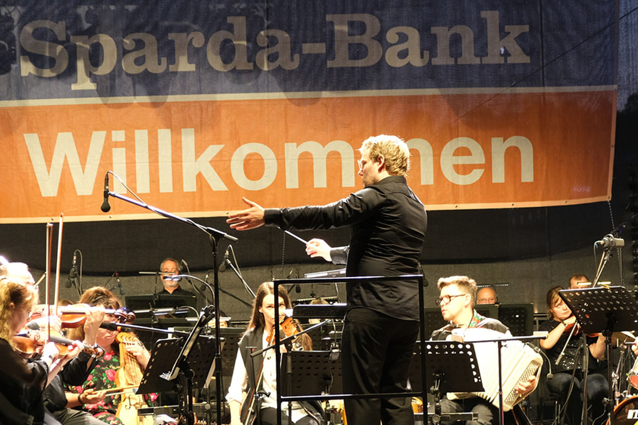 Das Orchester spielt vor einem Banner der Sparda-Bank