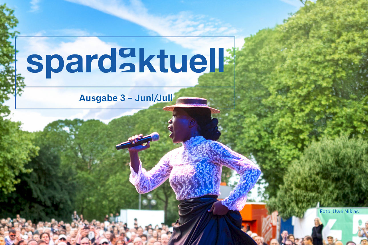 Eine Frau singt und tanzt auf einer Freilichtbühne vor Zuschauern