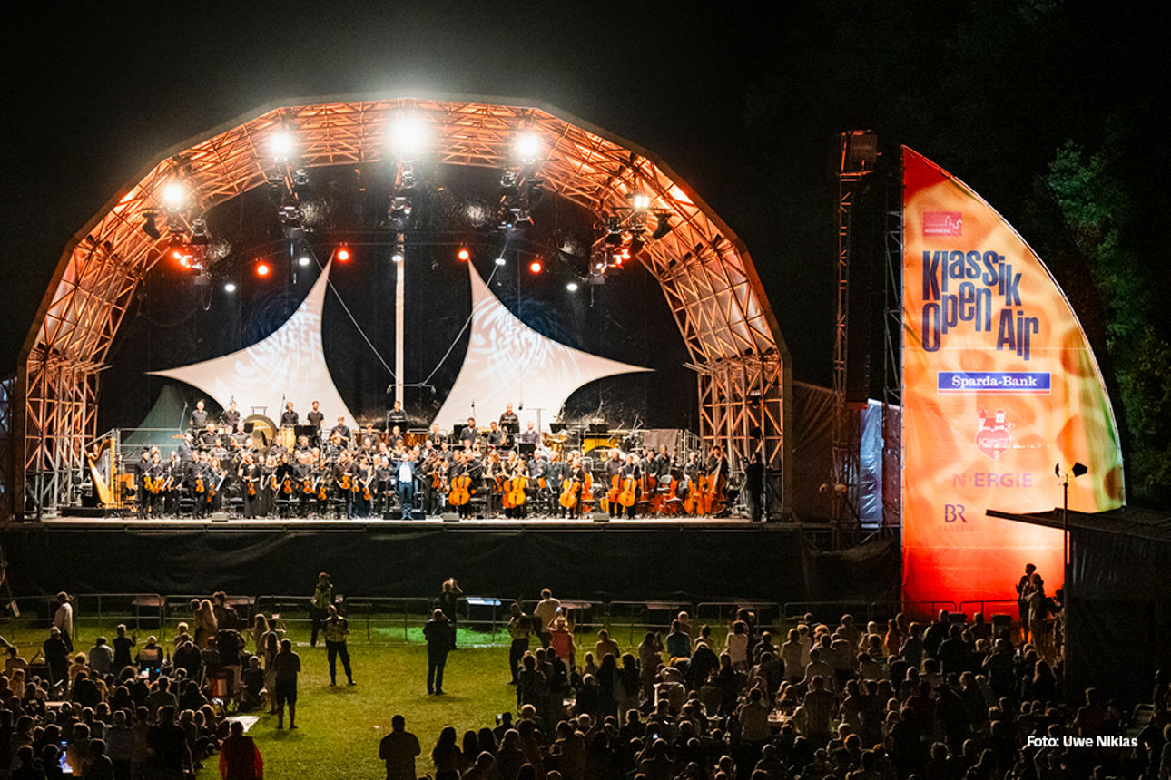 Die beleuchtete Konzertbühne des Klassik Open Airs und Zuschauer bei Nacht