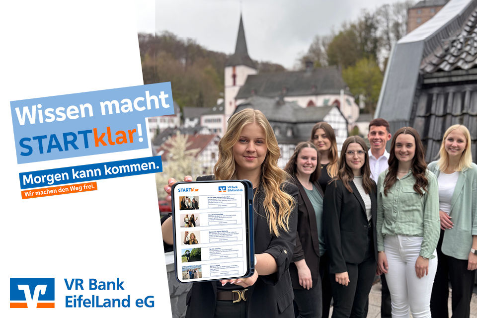Mehrer Azubis stehen zusammen und eine hält ein Tablet in der Hand und zeigt es in die Kamera