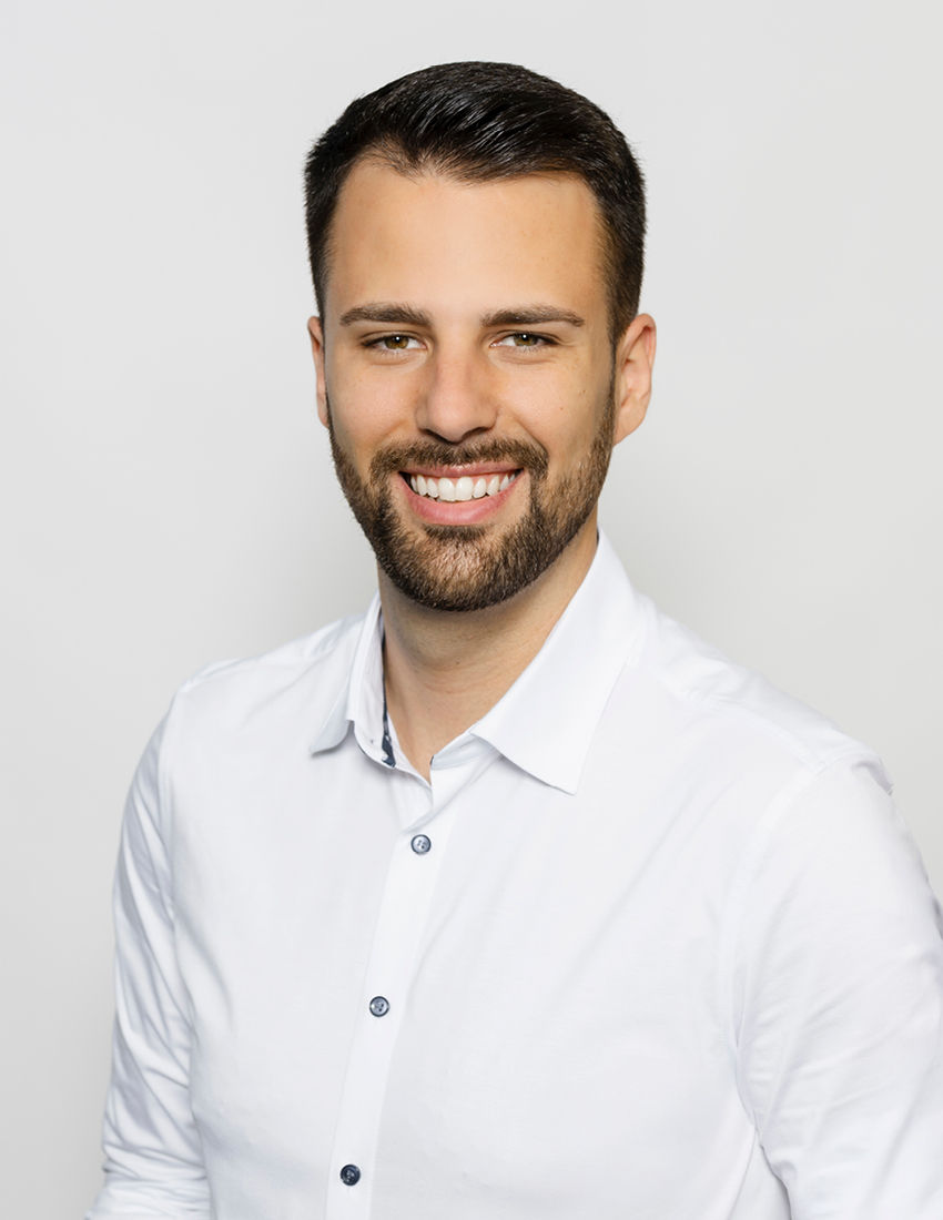 Foto unseres Vermögensberaters Daniel Rodriguez Lopez vor einem grauen Hintergrund in einem weißen Hemd