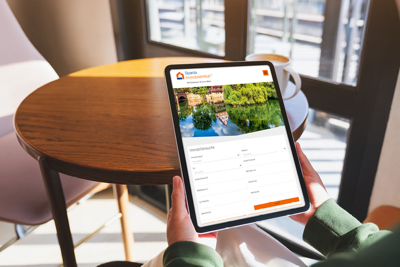 Eine Frau sieht sich auf einem Tablet die Seite der SpardaImmobilienwelt an