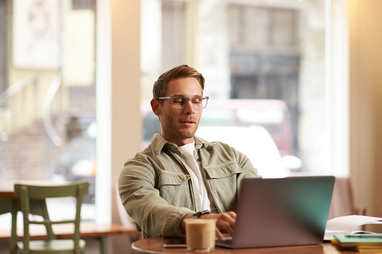 Mann mit Laptop sitzt in einem Cafe