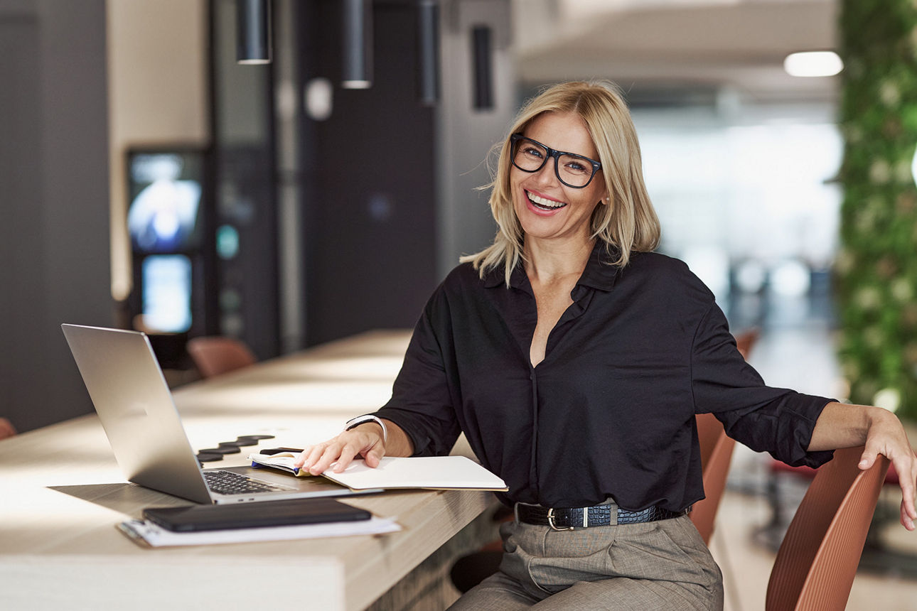 Frau am Schreibtisch im Büro mit Laptop und Unterlagen
