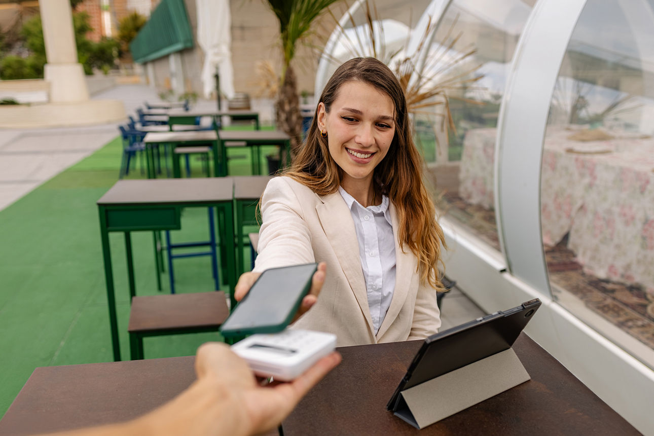 Junge Frau beim mobilen Bezahlen mit dem Handy
