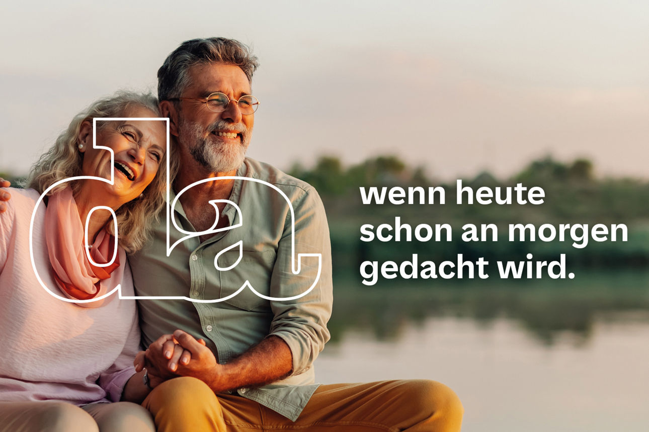 Älteres Paar sitzt eng umschlungen am Bug eines Boots hält Händchen und lacht gemeinsam während die Sonne untergeht