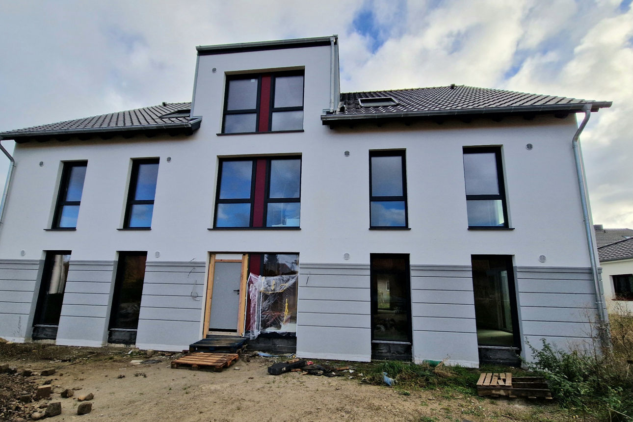 Ein modernes Haus mit einem Balkon und einem Dach unter einem klaren blauen Himmel.