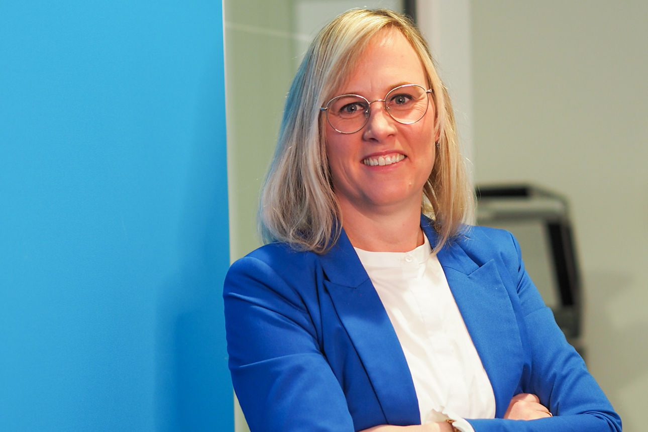 Frau in blauem Blazer lehnt an Wand an