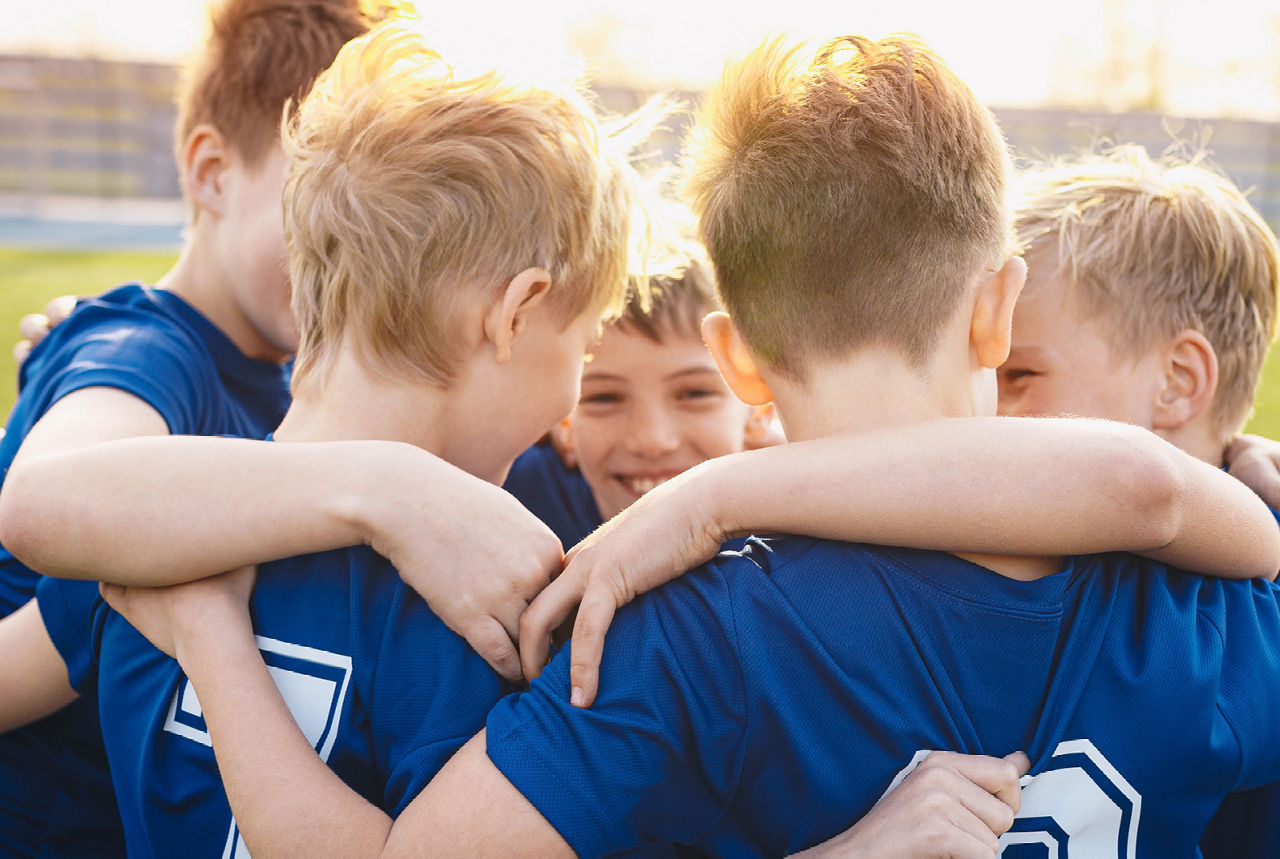 Mehrere Jungs besprechen sich auf einem Fussballfeld.