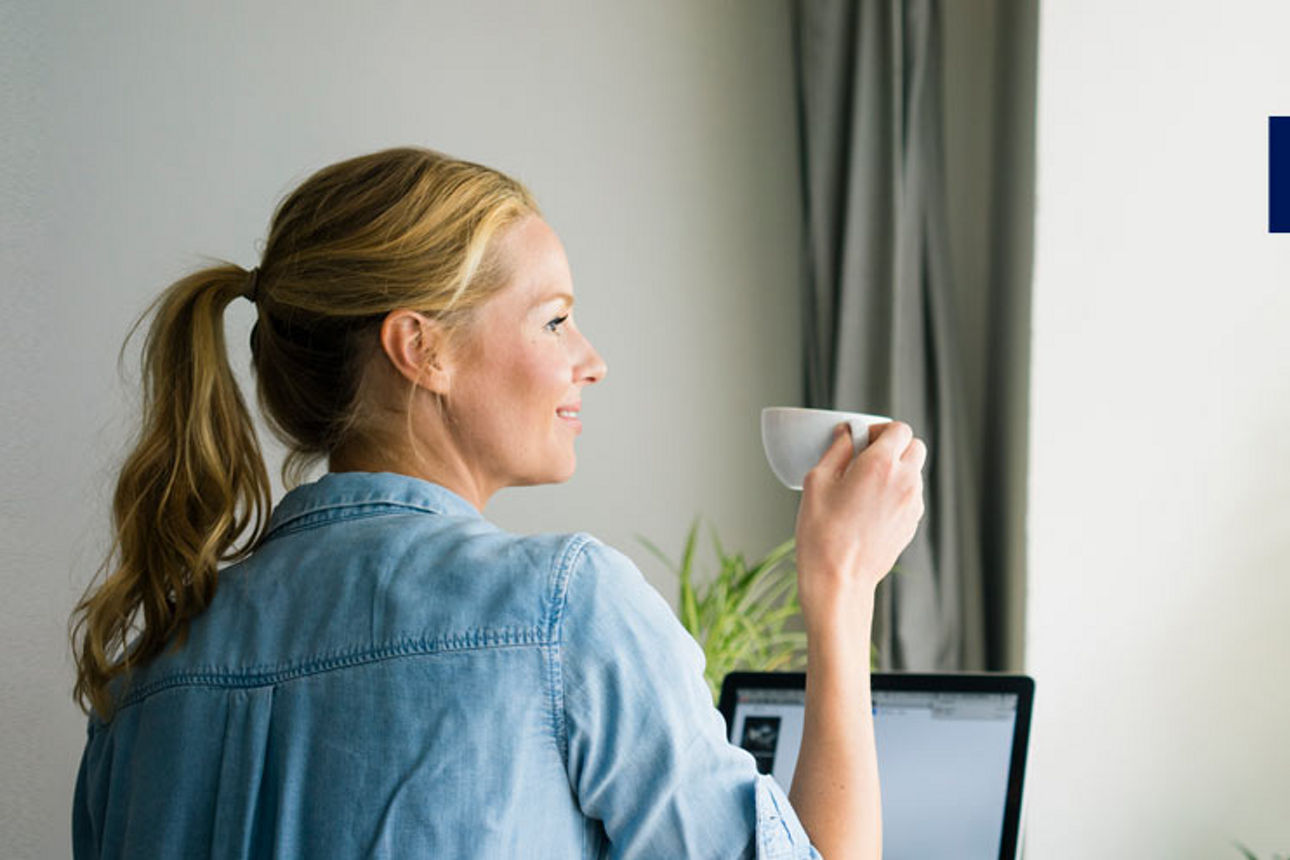 Frau schaut mit Kafee-Tasse in der Hand aus dem Fenster