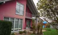 ein zweistöckiges Haus mit einer leuchtend rosa Fassade
