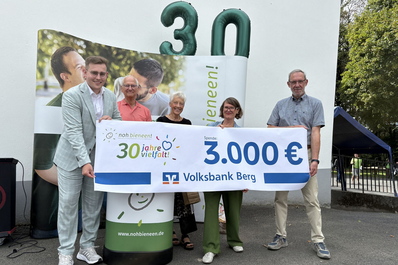 Zwei Frauen und drei Männer stehen vor einem Gebäude und halten ein Plakat