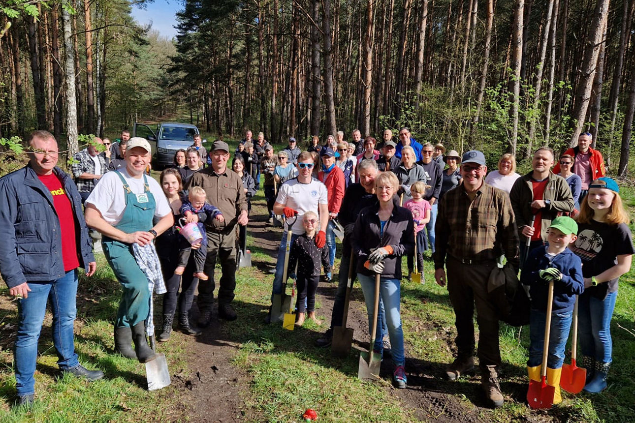 Ein Gruppe von circa 50 Menschen mit Spaten im Wald