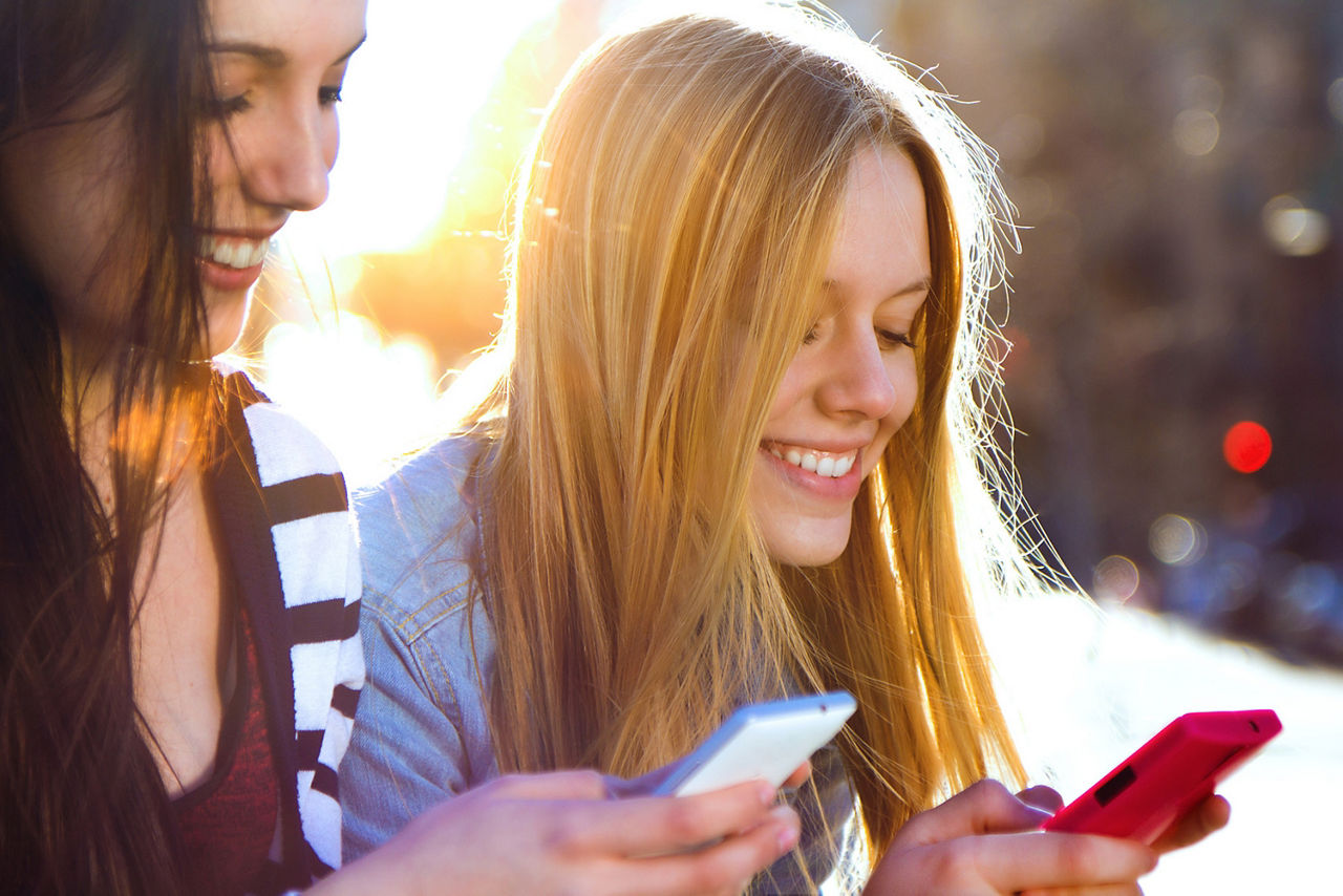 zwei Frauen sitzen nebeneinander und schauen auf ihr Smartphone