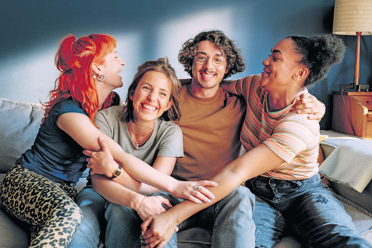 Vier junge Leute sitzen auf dem Sofa und umarmen sich