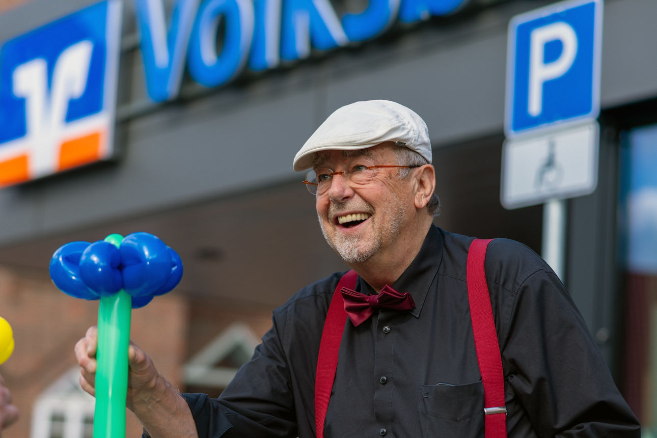 Ballonkünstler Bernd Knobloch mit einer Ballon-Blume vor der Volksbank