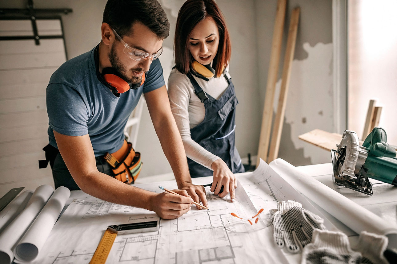 Mann und Frau besprechen einen Bauplan auf einer Baustelle