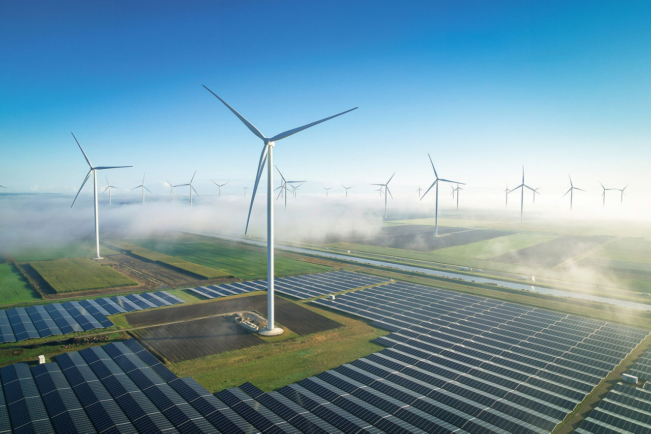 Viele Windkrafträder stehen auf einem großen Solarfeld