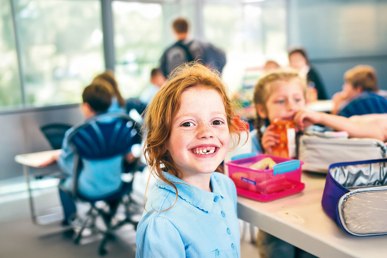 Lächelndes Schulkind sitzt in einer Schulklasse